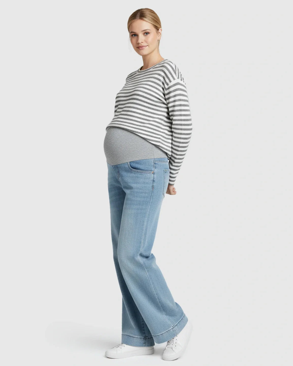 Maternity model in light wash wide leg jeans with folded hem and grey belly band, paired with a striped top.