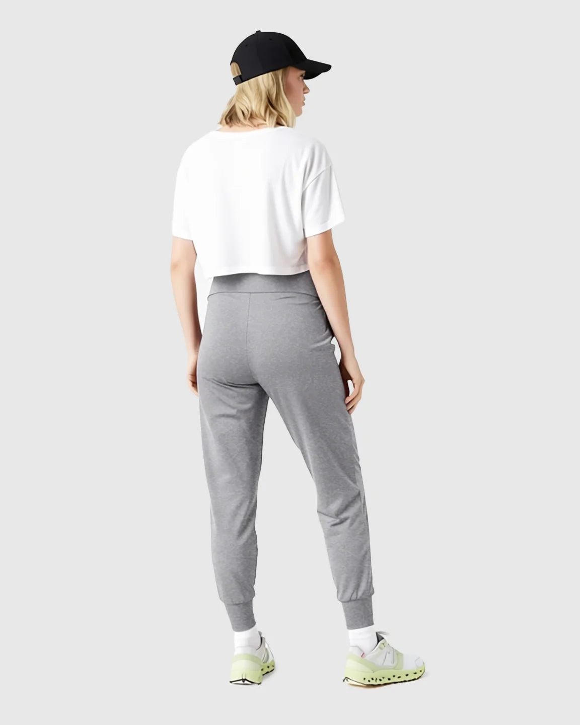 Woman from behind wearing gray slim-fitting maternity joggers with a high-waist and white cropped tee.