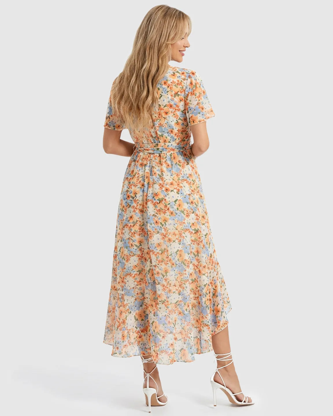 Blonde model in a floral V-neck ruffled hem maternity midi dress with a tie waist, back view.