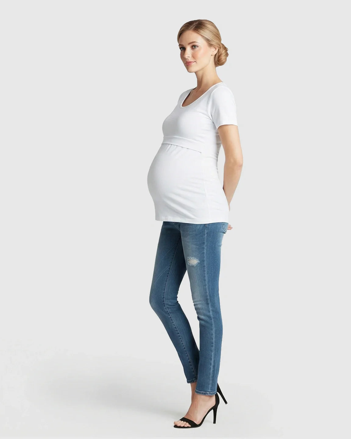 Pregnant woman in white stretch-fit V-neck nursing t-shirt and blue jeans.