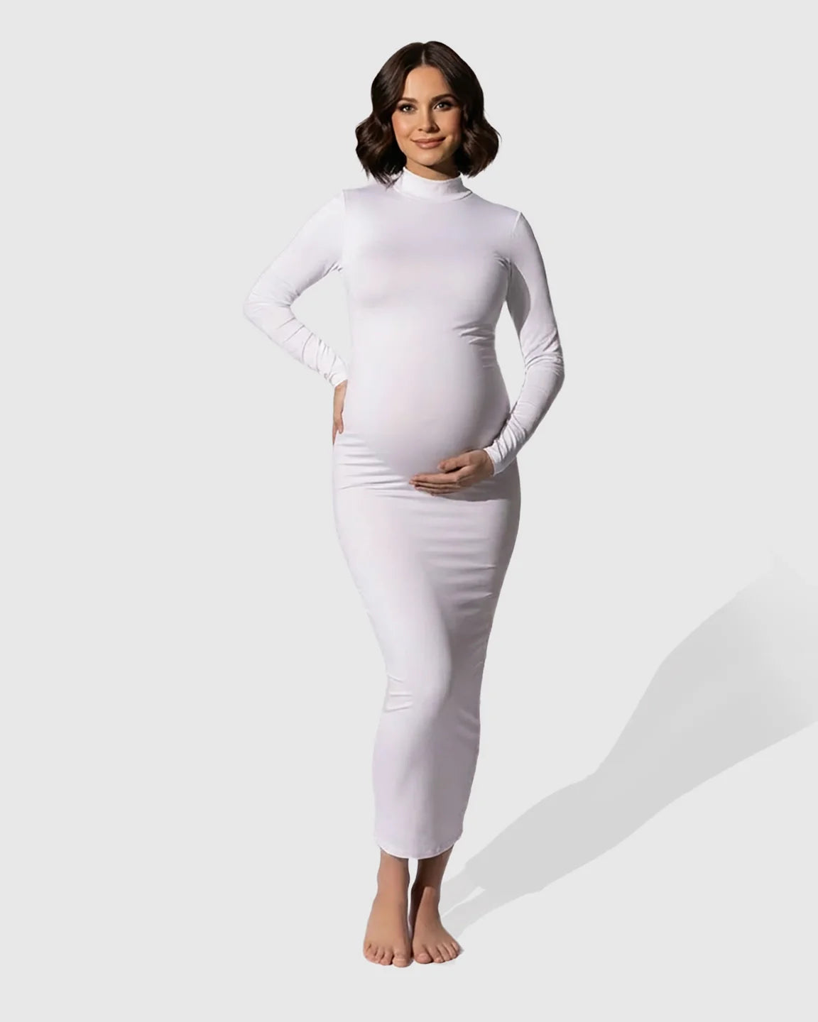 Smiling pregnant woman in a white long-sleeve mock-neck bodycon maternity maxi dress.
