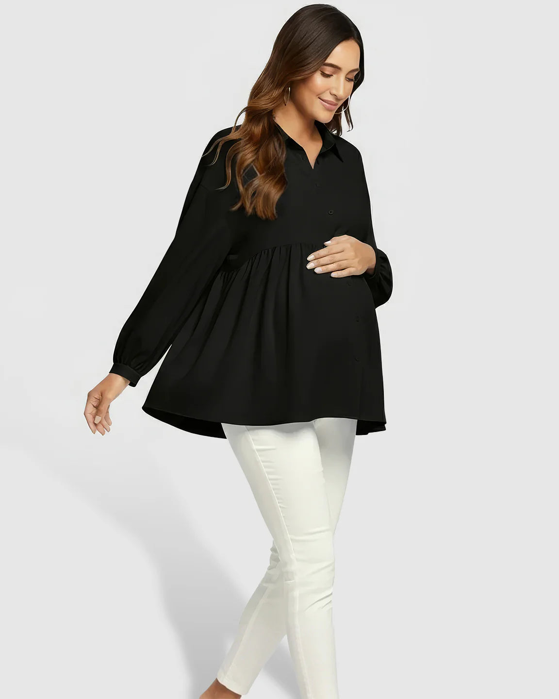 Maternity model wearing a black chiffon lapel long sleeve babydoll shirt with white pants, holding her bump.