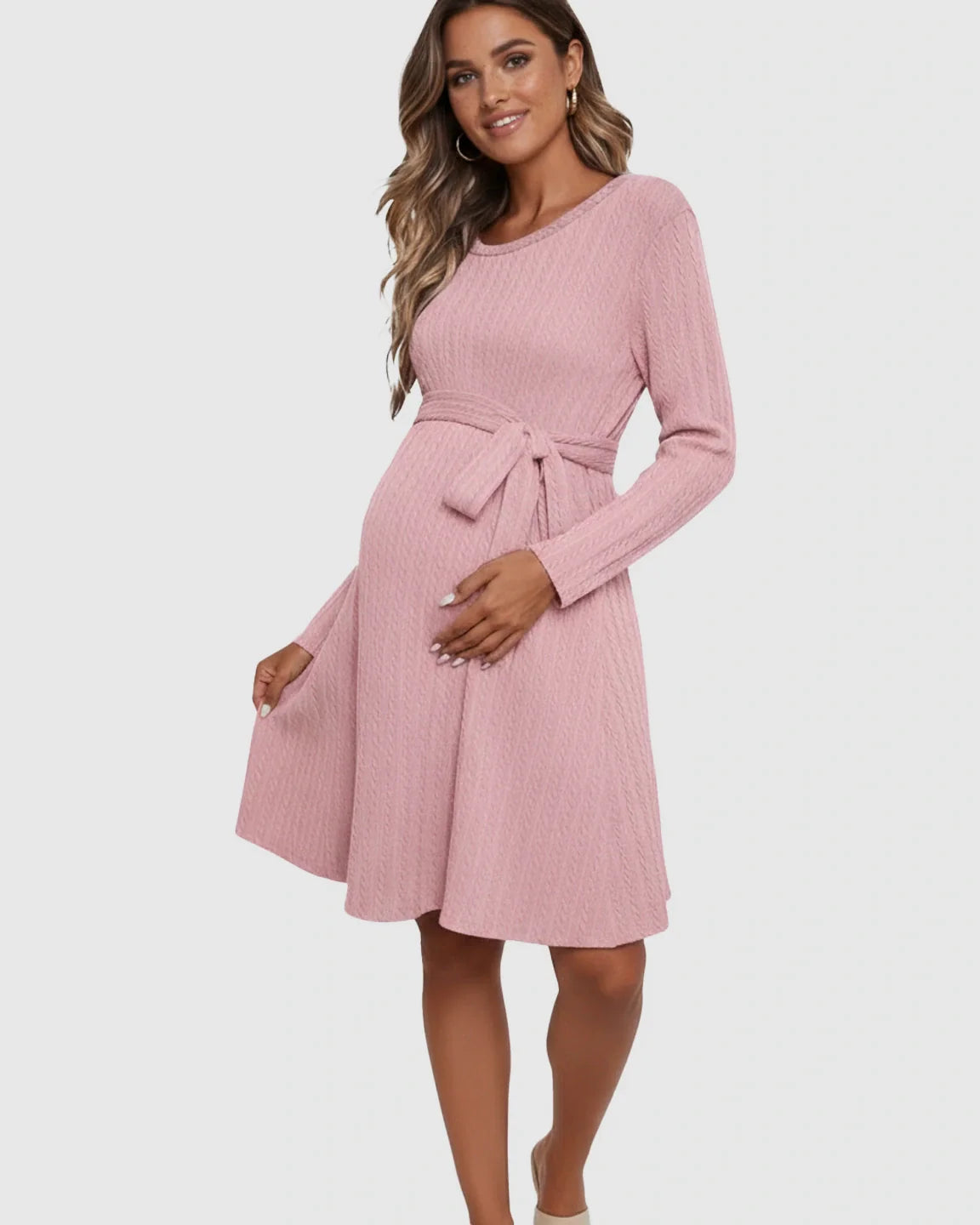 Smiling pregnant woman in a pink ribbed tie-waist maternity midi dress with long sleeves.