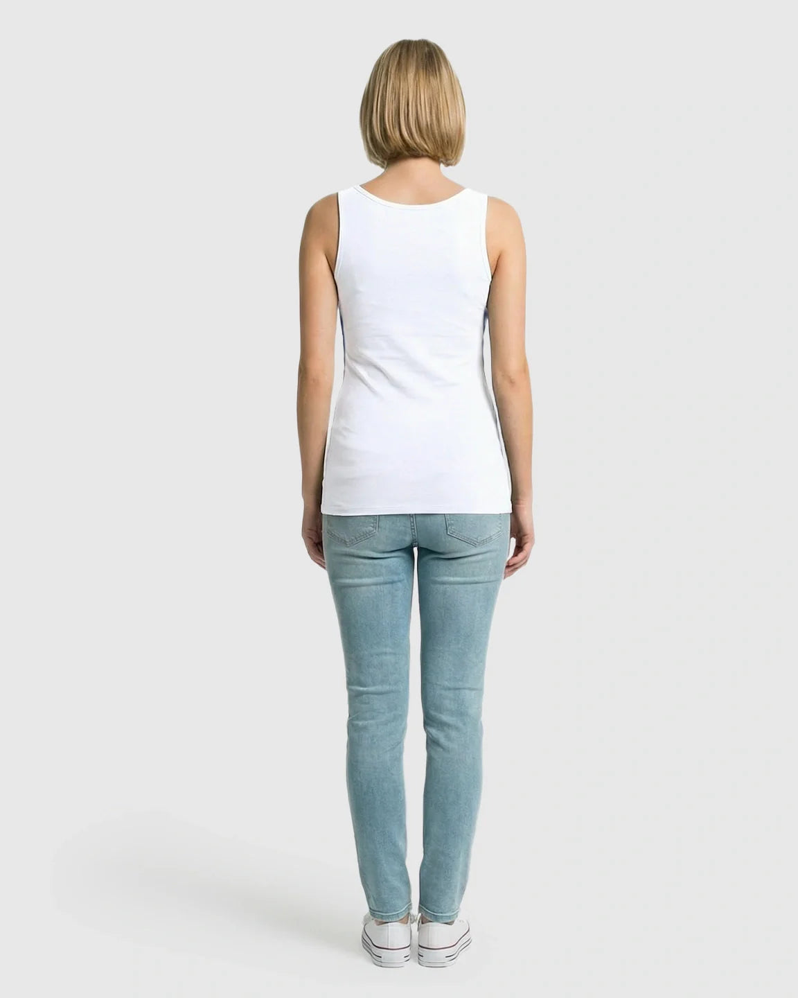 Back view of a woman wearing a white stretch nursing-access maternity tank top and light blue jeans.