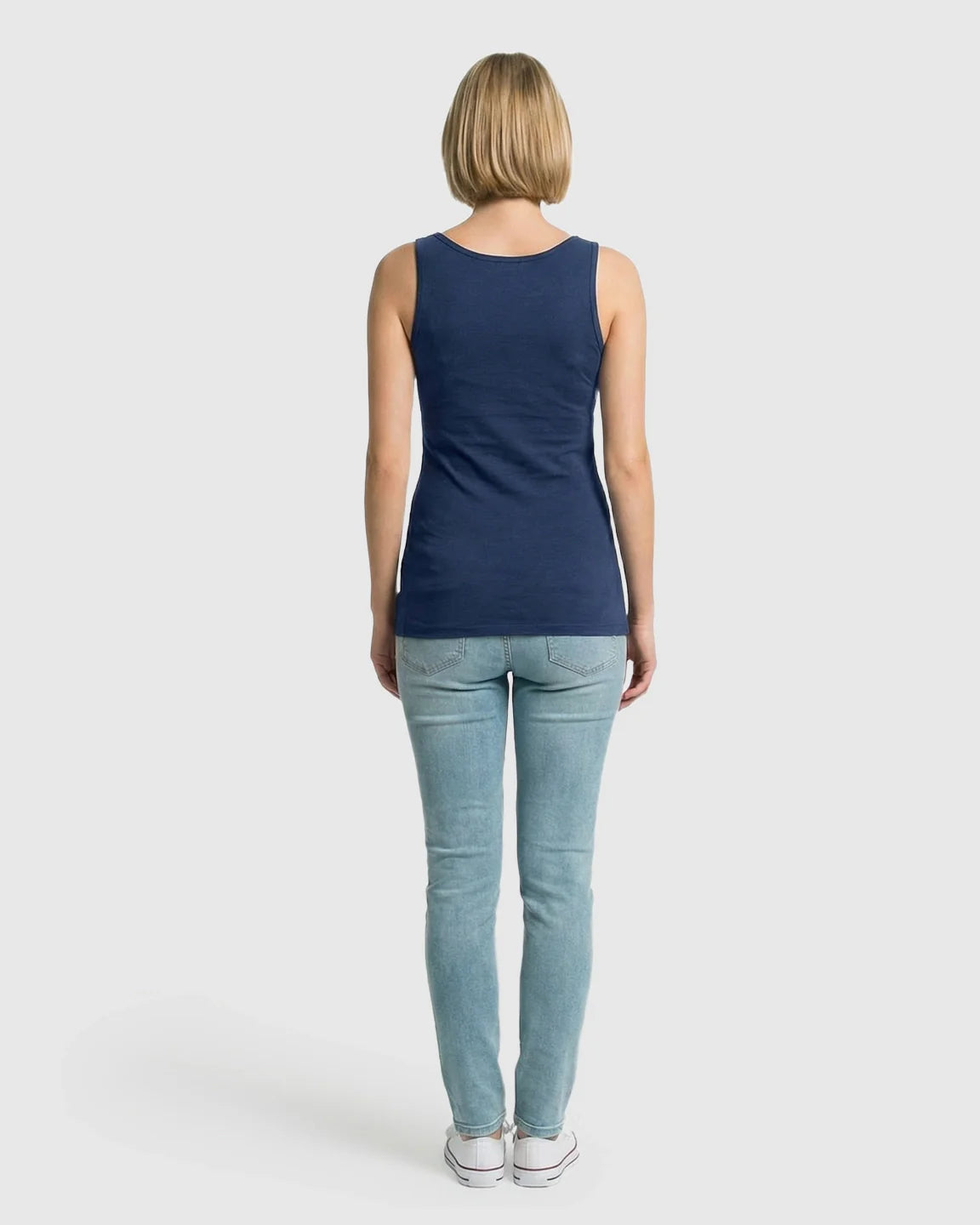 Woman from behind wearing a navy blue stretch nursing-access maternity tank top and light wash jeans.