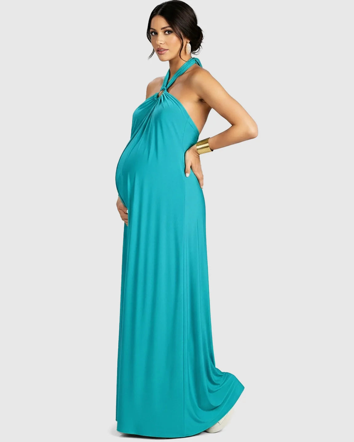 Maternity model in a turquoise backless halter neck chiffon maxi dress with a flowing skirt.