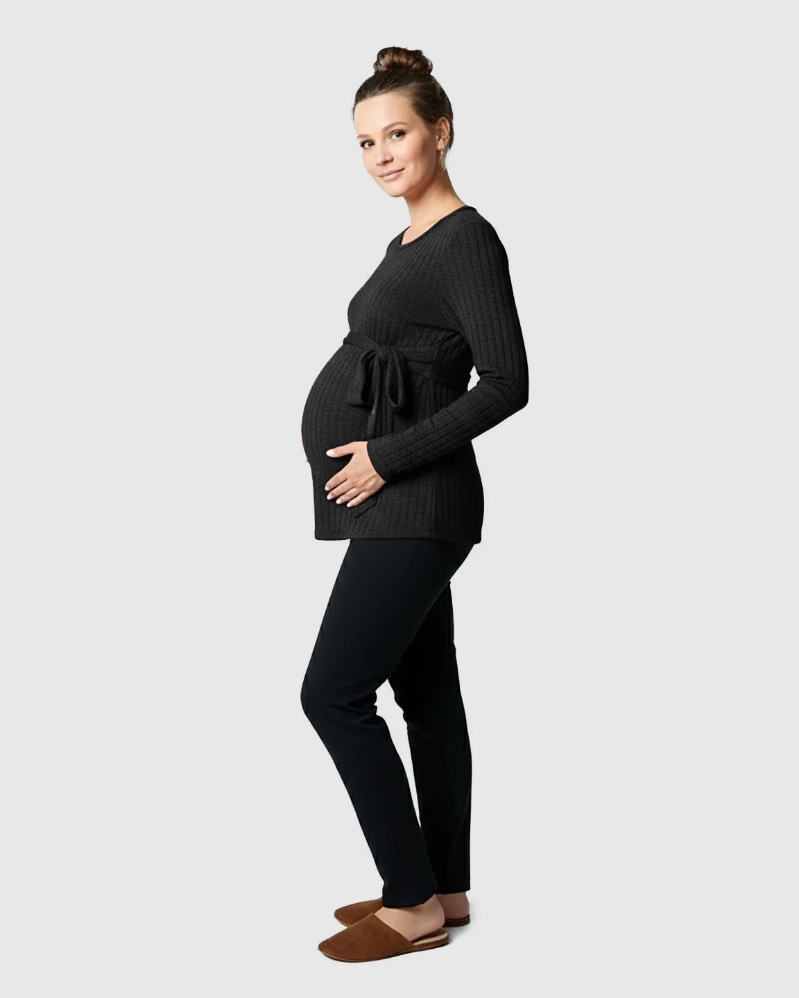 Pregnant woman in a black ribbed tie-waist long sleeve maternity sweater and black pants.