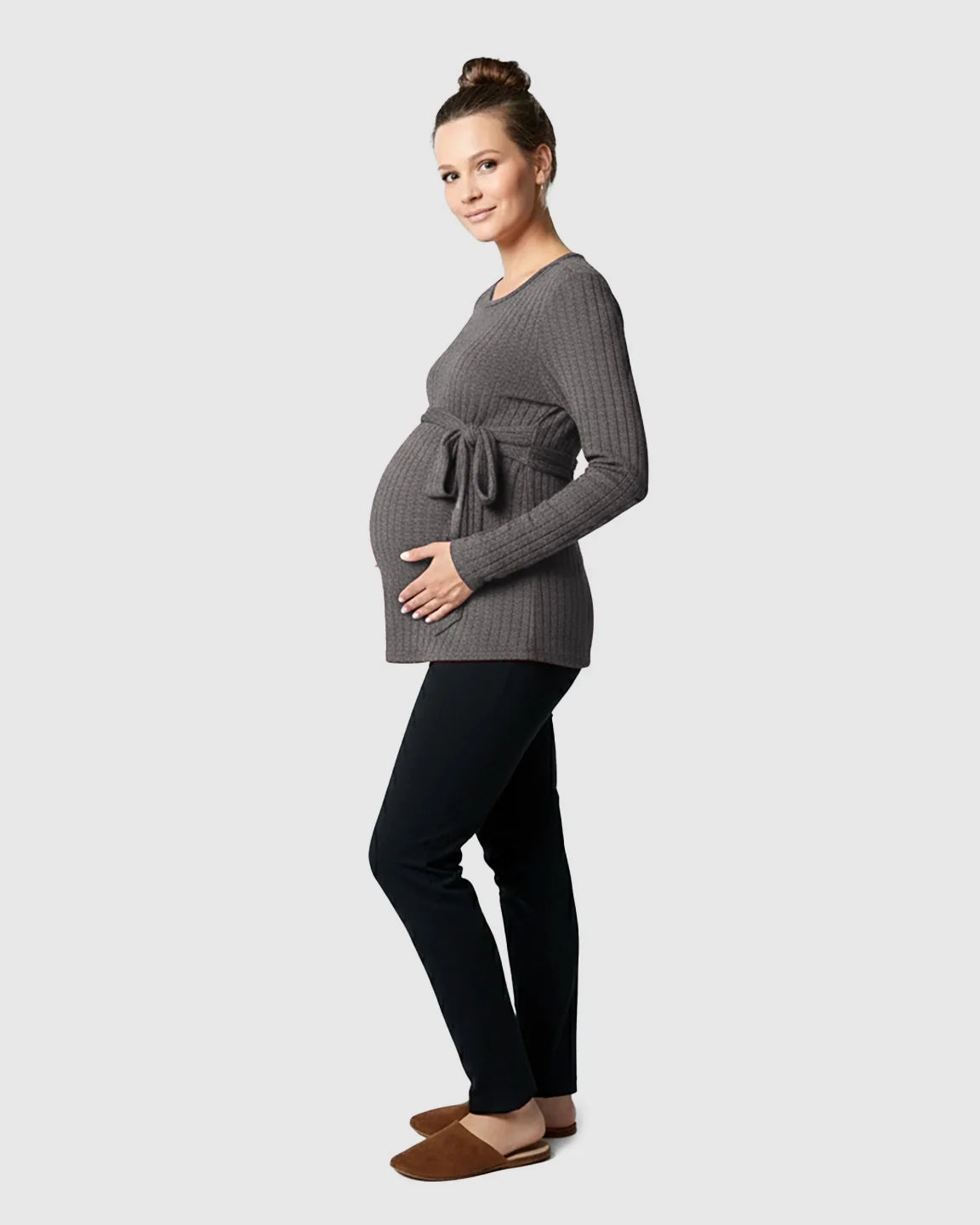 Pregnant woman in a charcoal ribbed tie-waist long sleeve maternity sweater and black pants.
