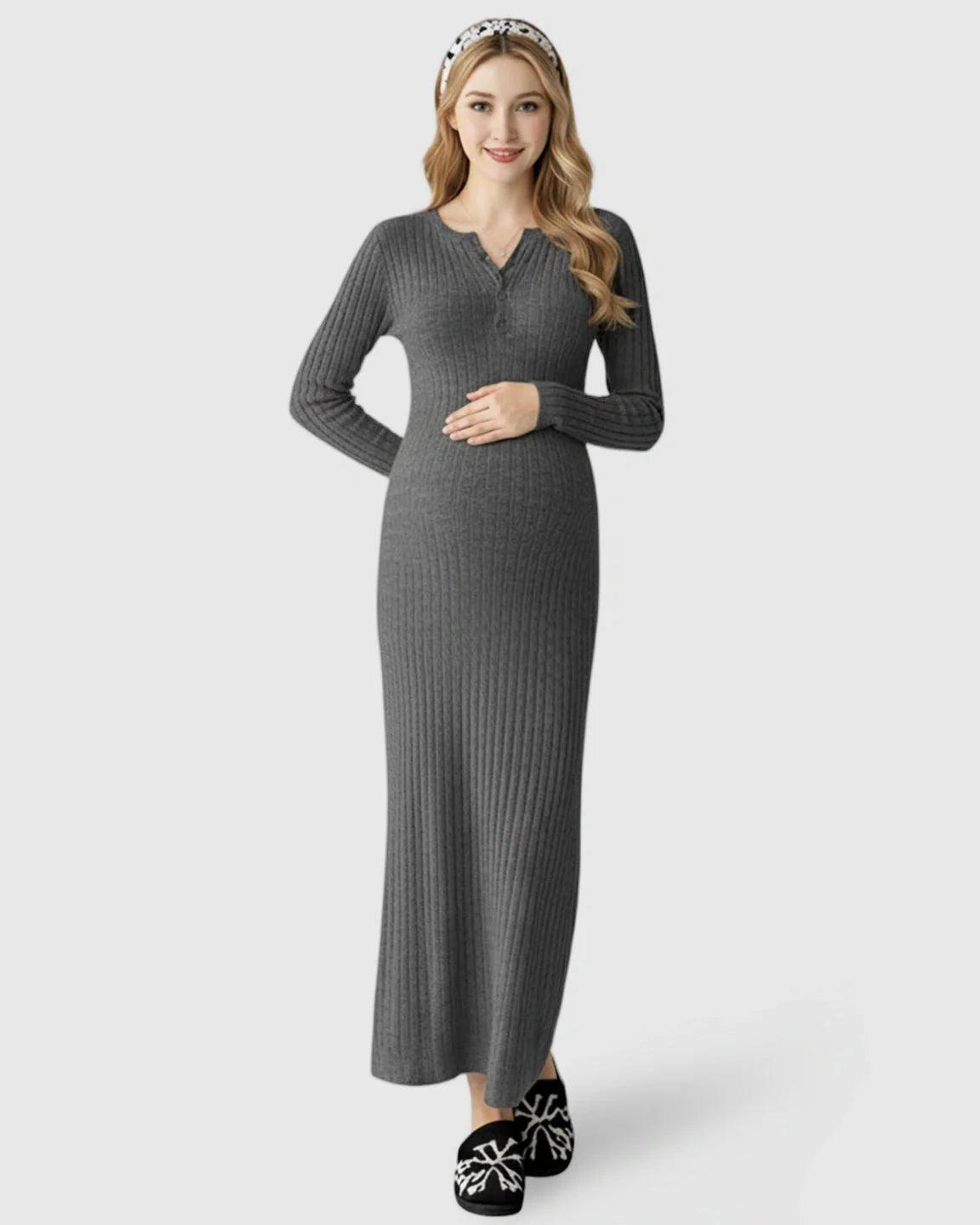 Smiling pregnant woman in a gray ribbed knit A-line long sleeve maternity maxi dress, holding her bump.