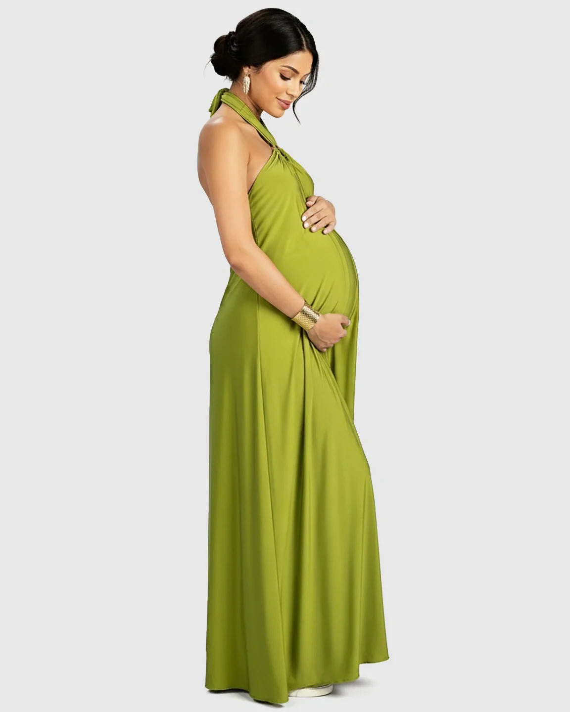 Maternity model in a flowing olive green backless halter neck maxi dress, cradling her bump.