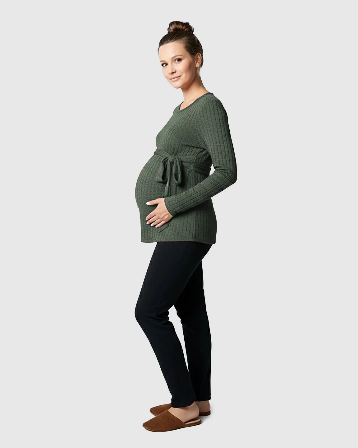 Pregnant woman in a green ribbed tie-waist long sleeve maternity sweater and black pants.