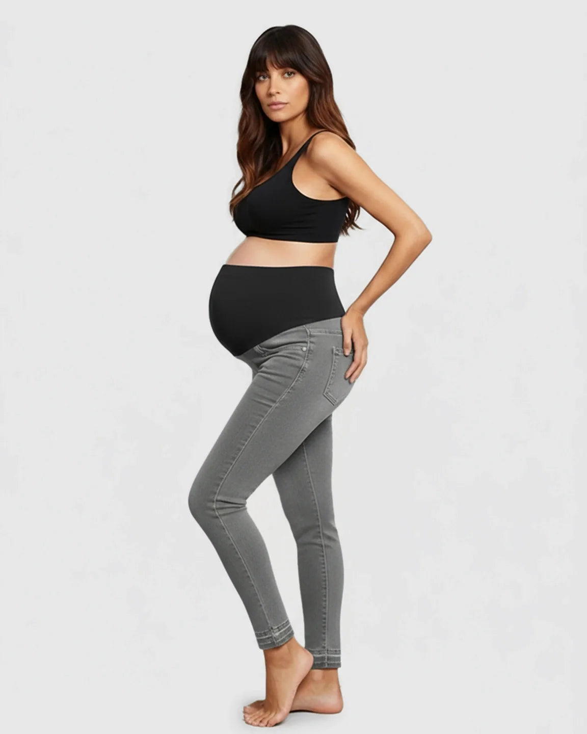 Pregnant woman in gray stretch high-waist skinny maternity jeans with a black elastic waistband.
