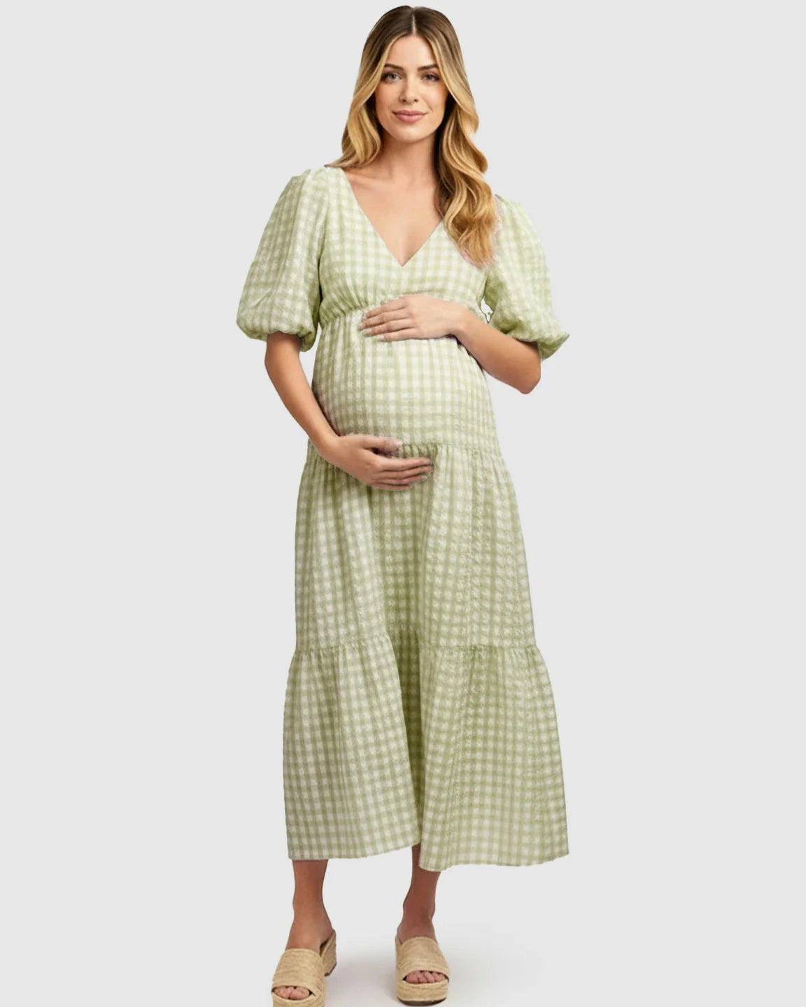 Pregnant woman in a green and white checkered maternity maxi dress with puffed sleeves.