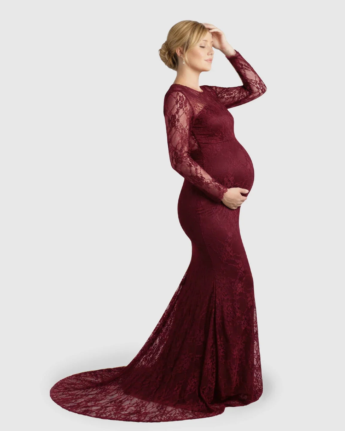Pregnant woman in a sheer lace trumpet maternity photoshoot gown in a rich burgundy color.