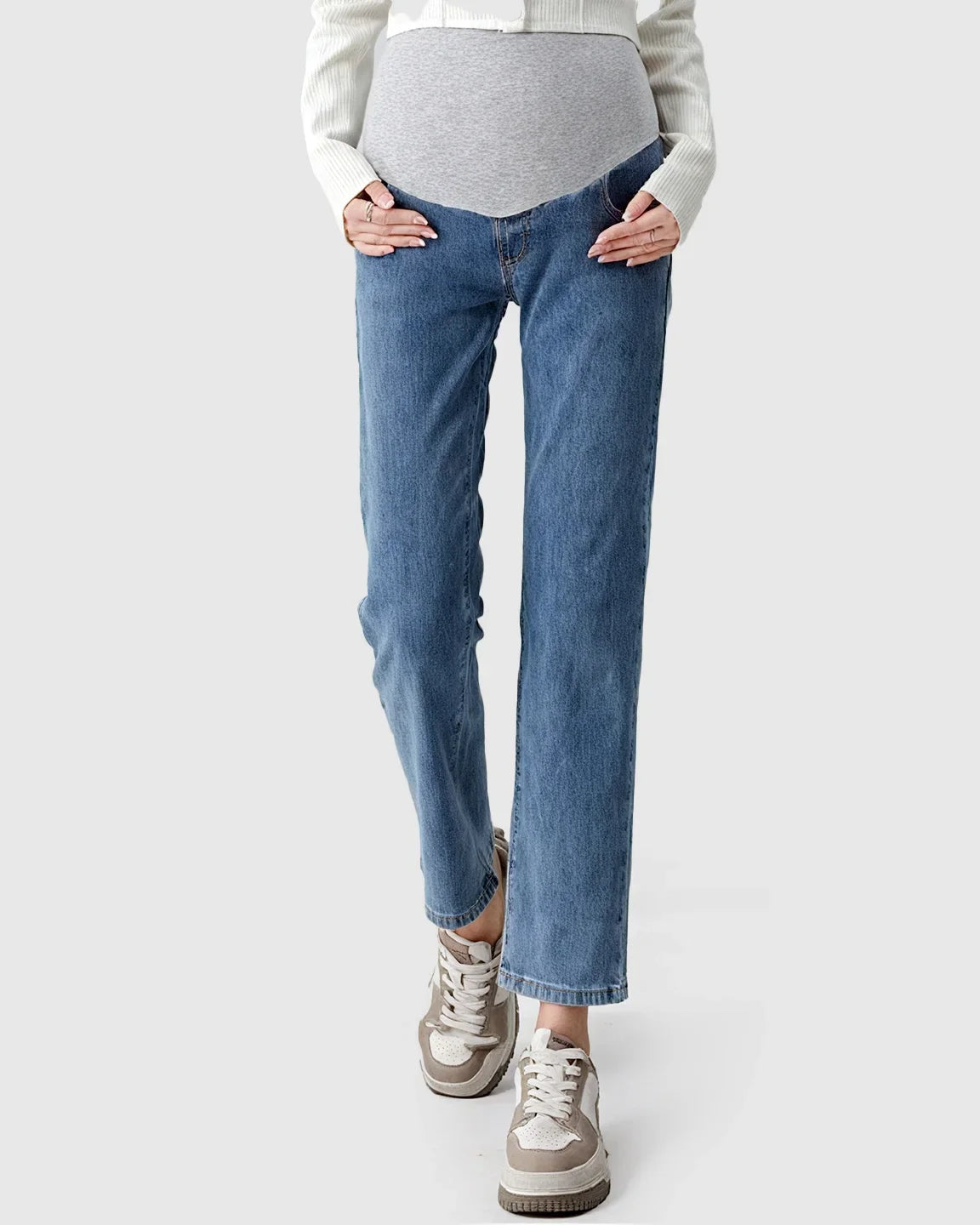 Woman wearing light wash straight-leg maternity jeans with a grey over-the-belly panel and white cardigan.