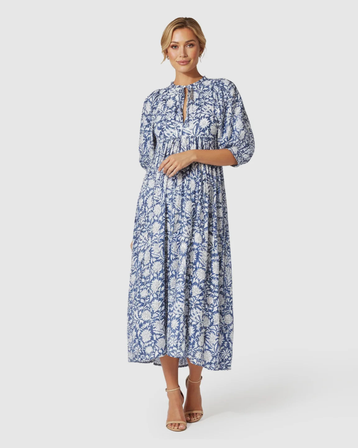 Woman in a blue and white floral loose-fit maternity midi dress with gathered shoulders and puff sleeves.