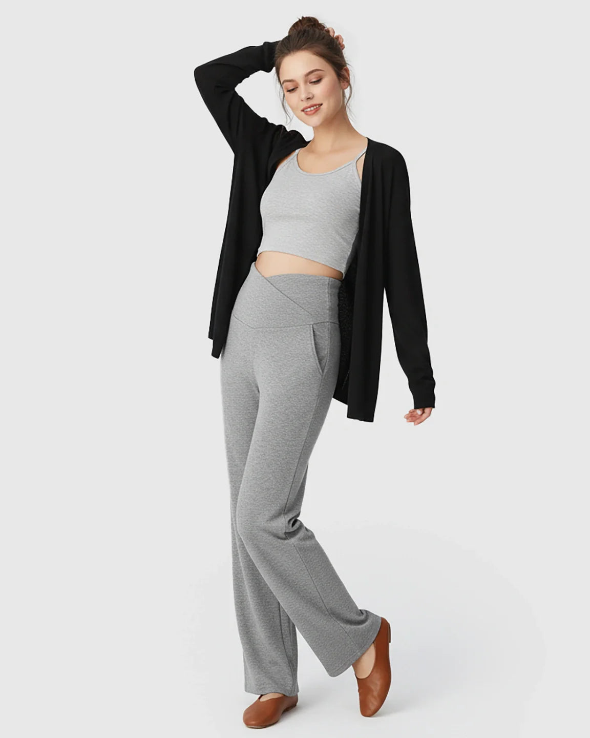 Woman in gray crossover waist wide-leg maternity lounge pants, gray crop top, and black cardigan.