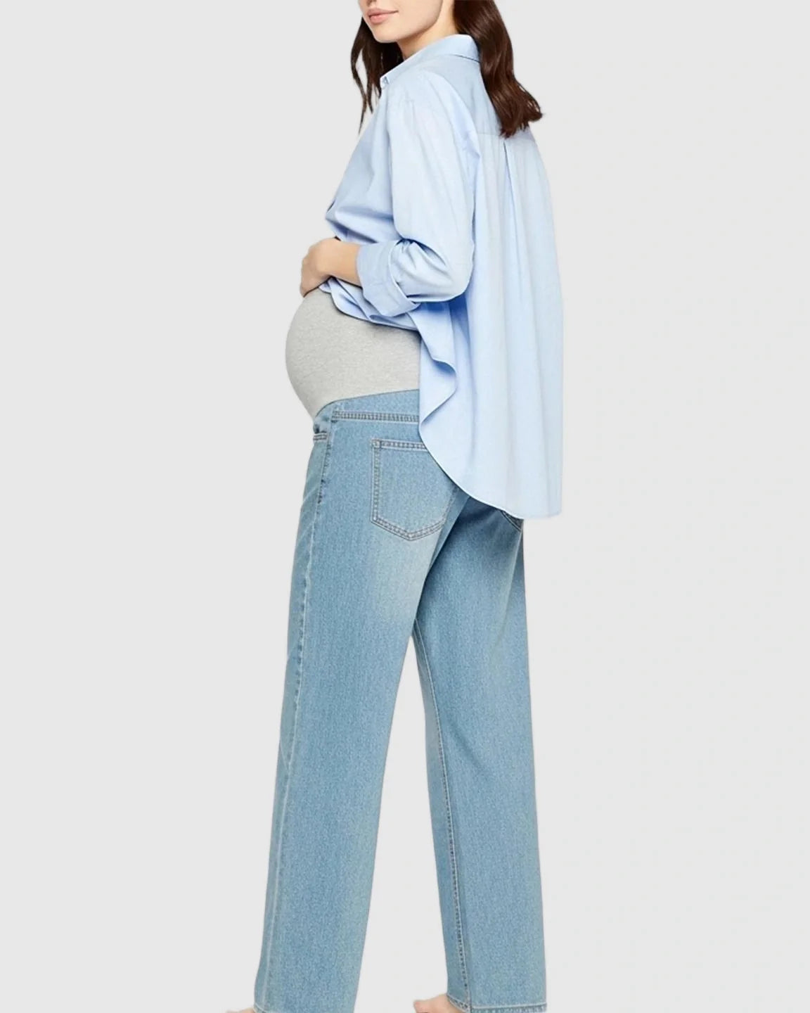 Maternity model in light blue straight-leg jeans with a grey belly band and a light blue button-up shirt.