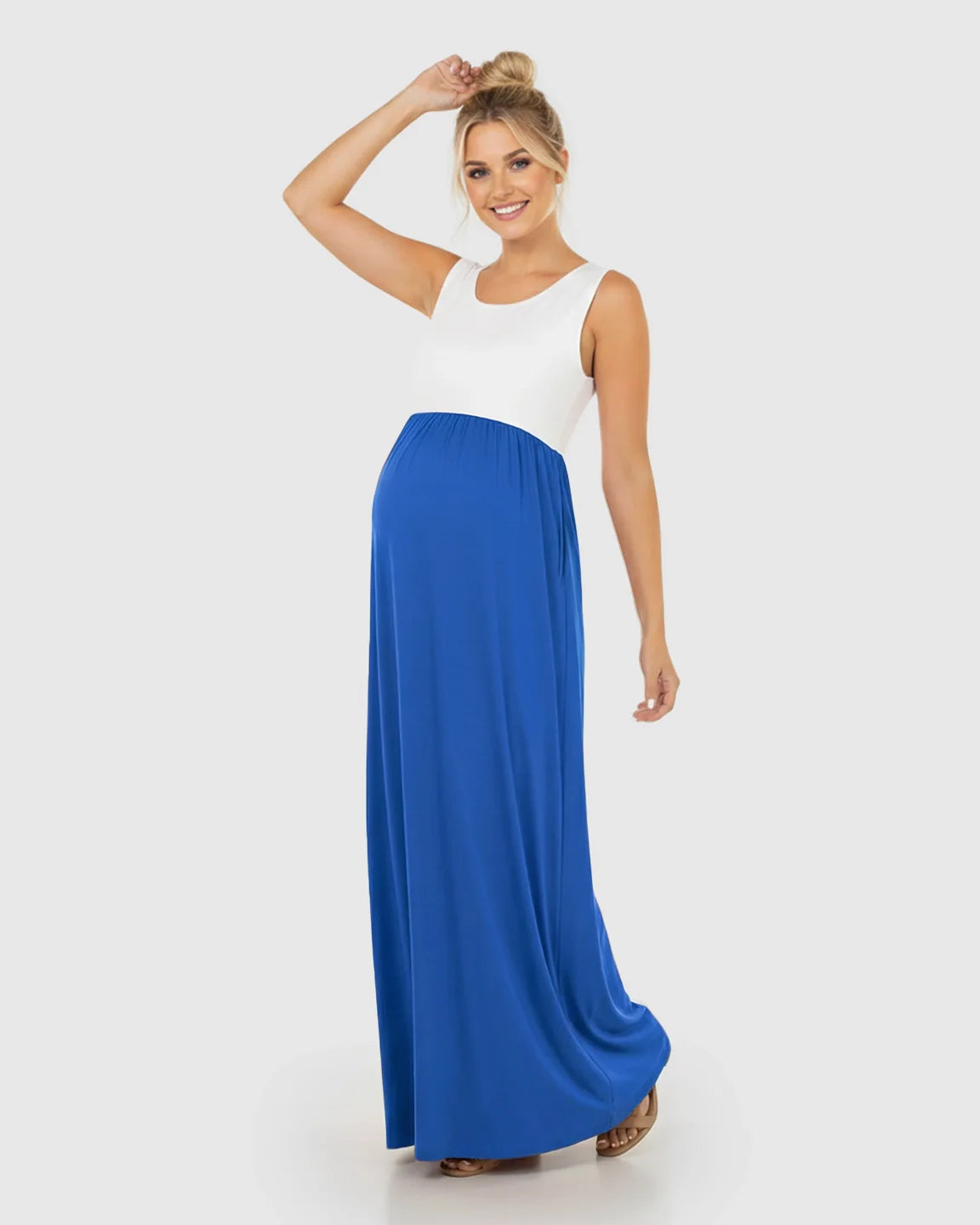 Smiling pregnant woman in a white and royal blue colorblock high-waisted maternity maxi dress.