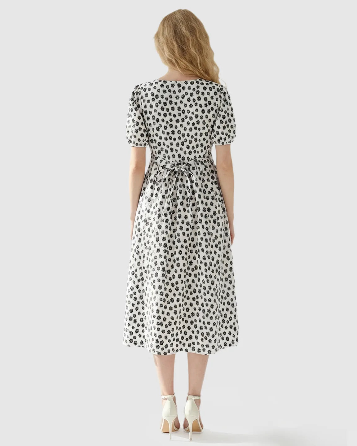 Woman from behind in a white floral print maternity nursing dress with a tie-back waist and short sleeves.