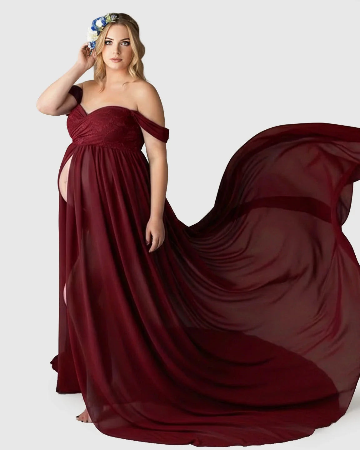 Pregnant woman in a flowing, off-shoulder burgundy chiffon maternity gown with an extra-long train.