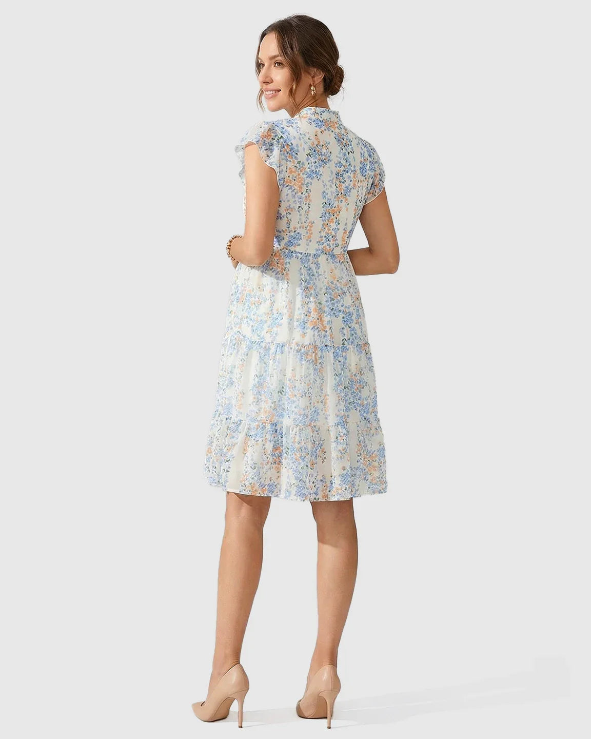 White chiffon A-line maternity dress with blue and orange floral print, flutter sleeves, and tiered skirt.