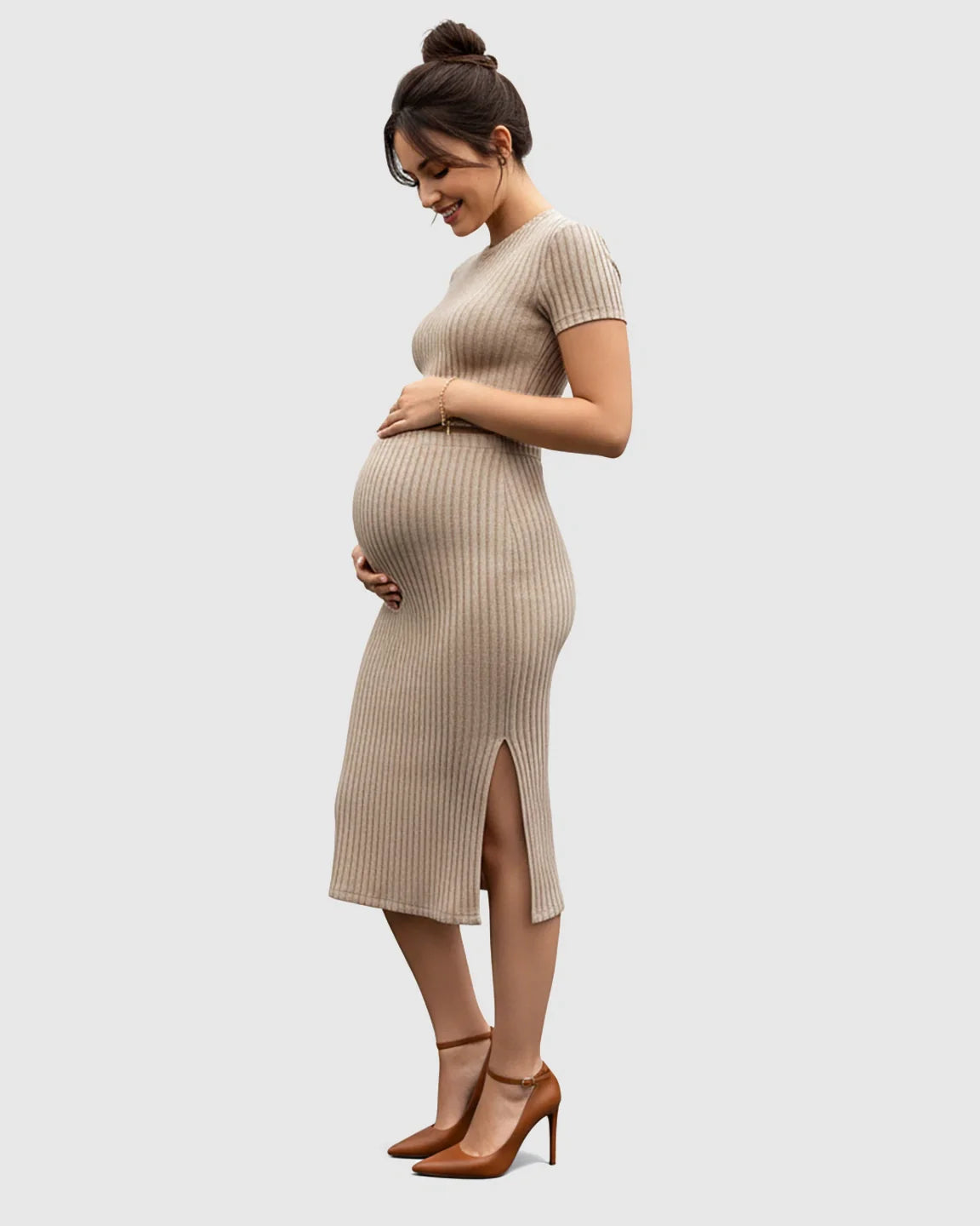 Smiling pregnant woman in a beige ribbed short-sleeve crop top and matching side-slit midi skirt.