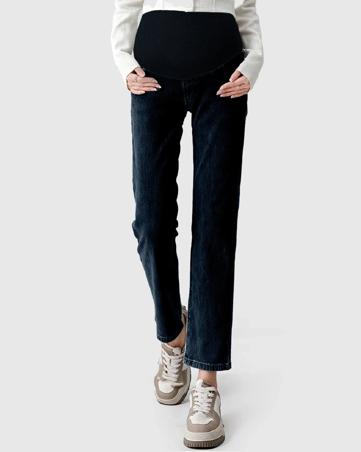 Dark wash straight-leg maternity jeans with a black over-the-belly panel, worn with a white cardigan and sneakers.