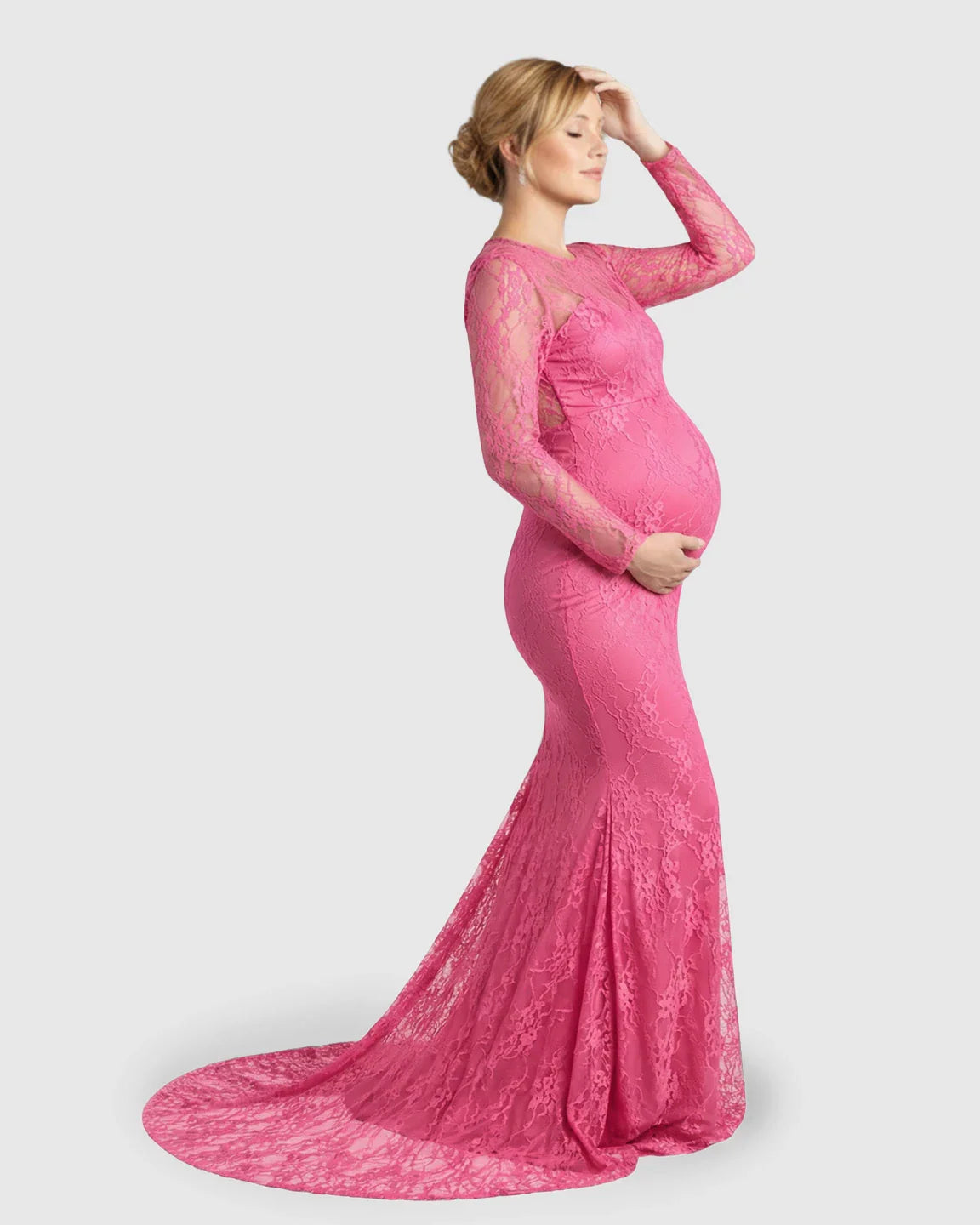 Pregnant woman in a pink sheer lace trumpet maternity photoshoot gown with long sleeves and a mermaid skirt.