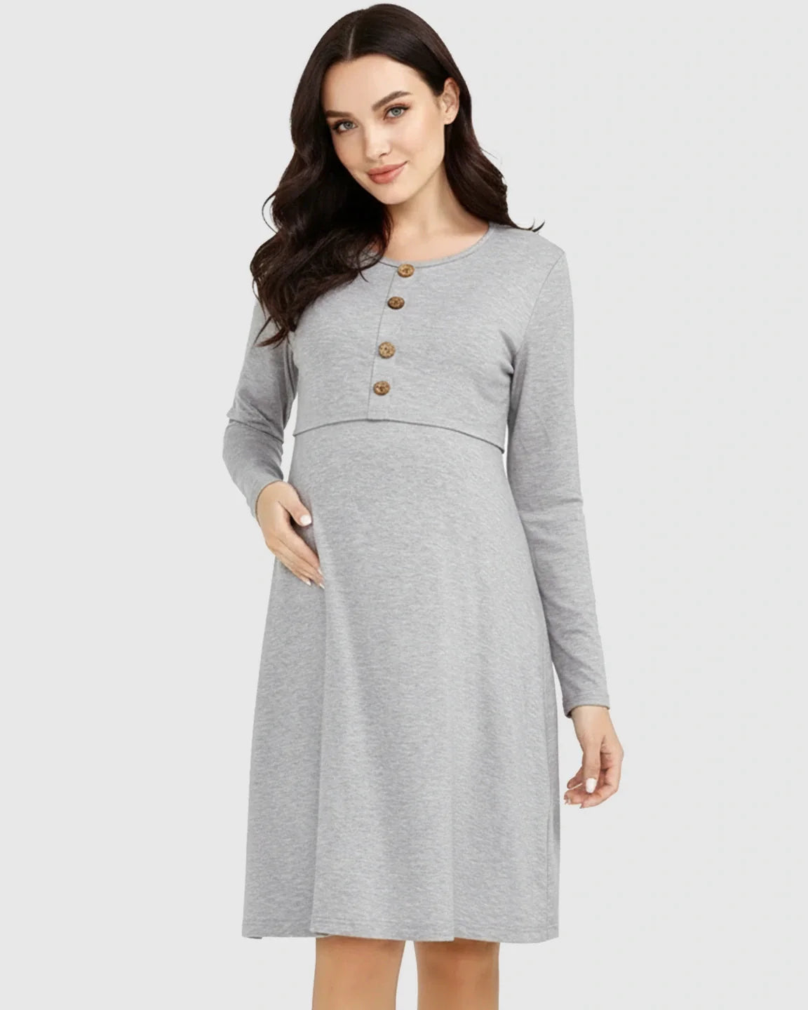 Woman in a grey long-sleeve empire waist nursing dress with button-front detail, gently touching her pregnant belly.