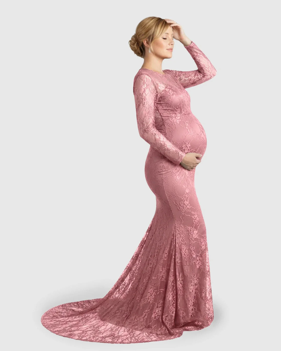 Pregnant woman in a pink sheer lace trumpet maternity photoshoot gown with long sleeves and a mermaid skirt.