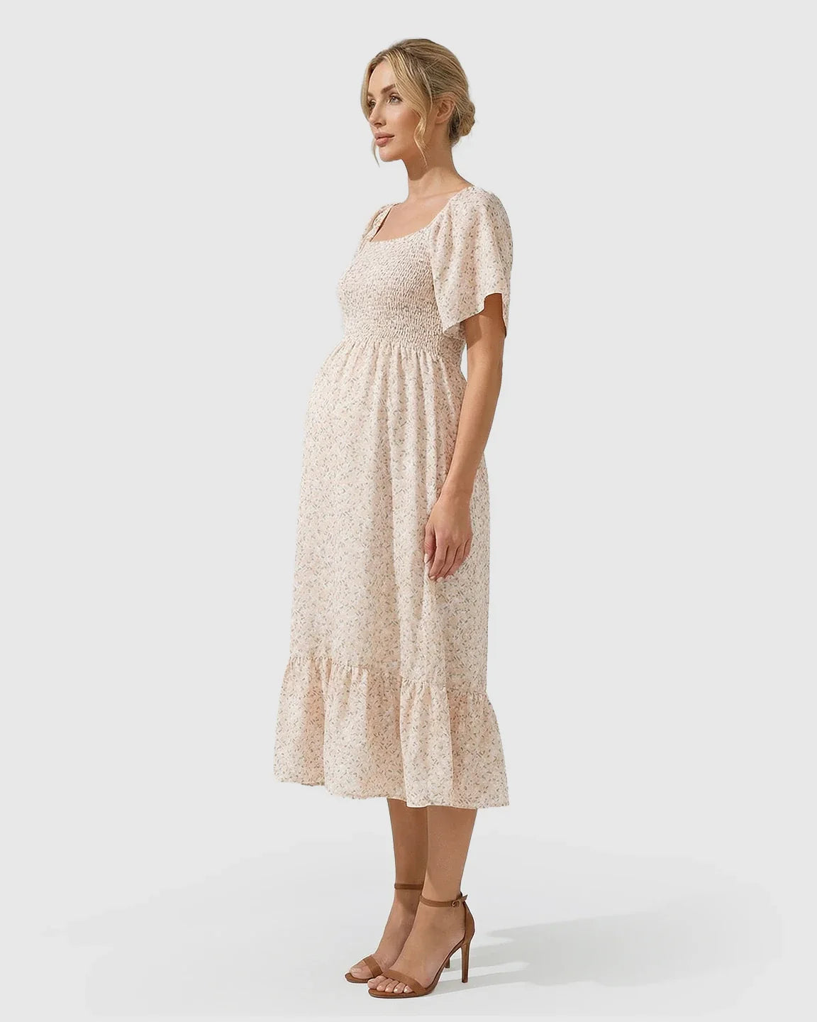 Maternity midi dress in light pink floral print with flutter sleeves, smocked bodice, and tiered skirt.