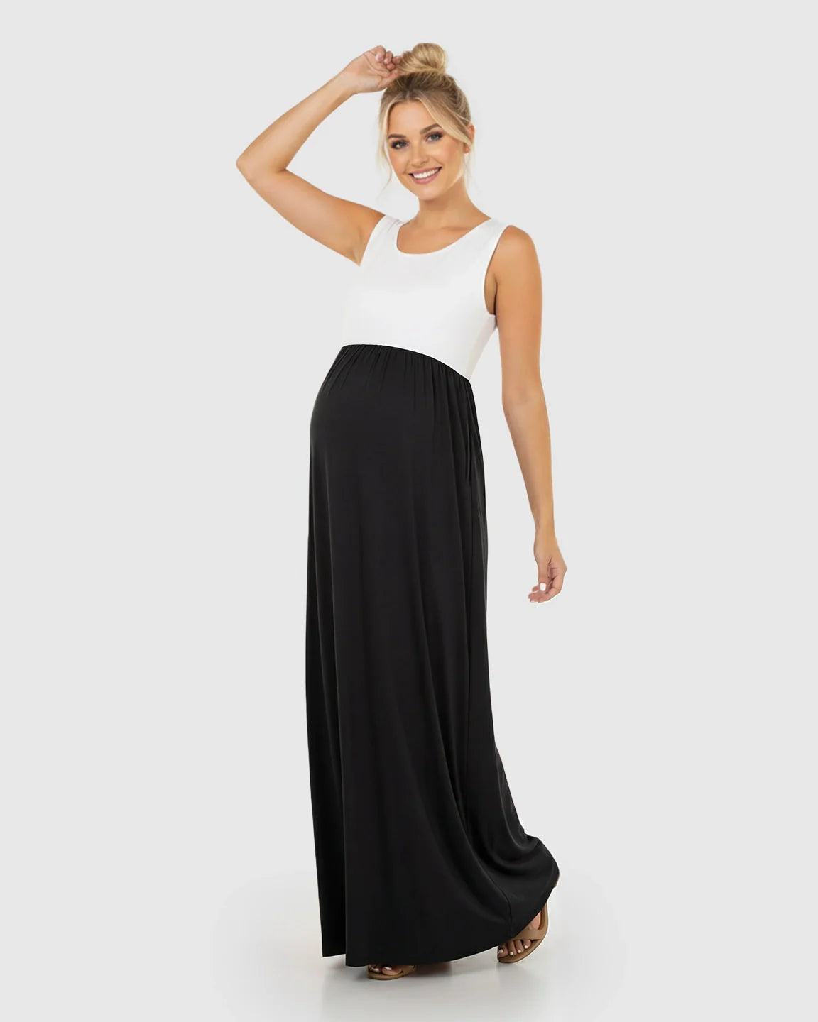Smiling pregnant woman in a sleeveless, white and black colorblock high-waisted maternity maxi dress.
