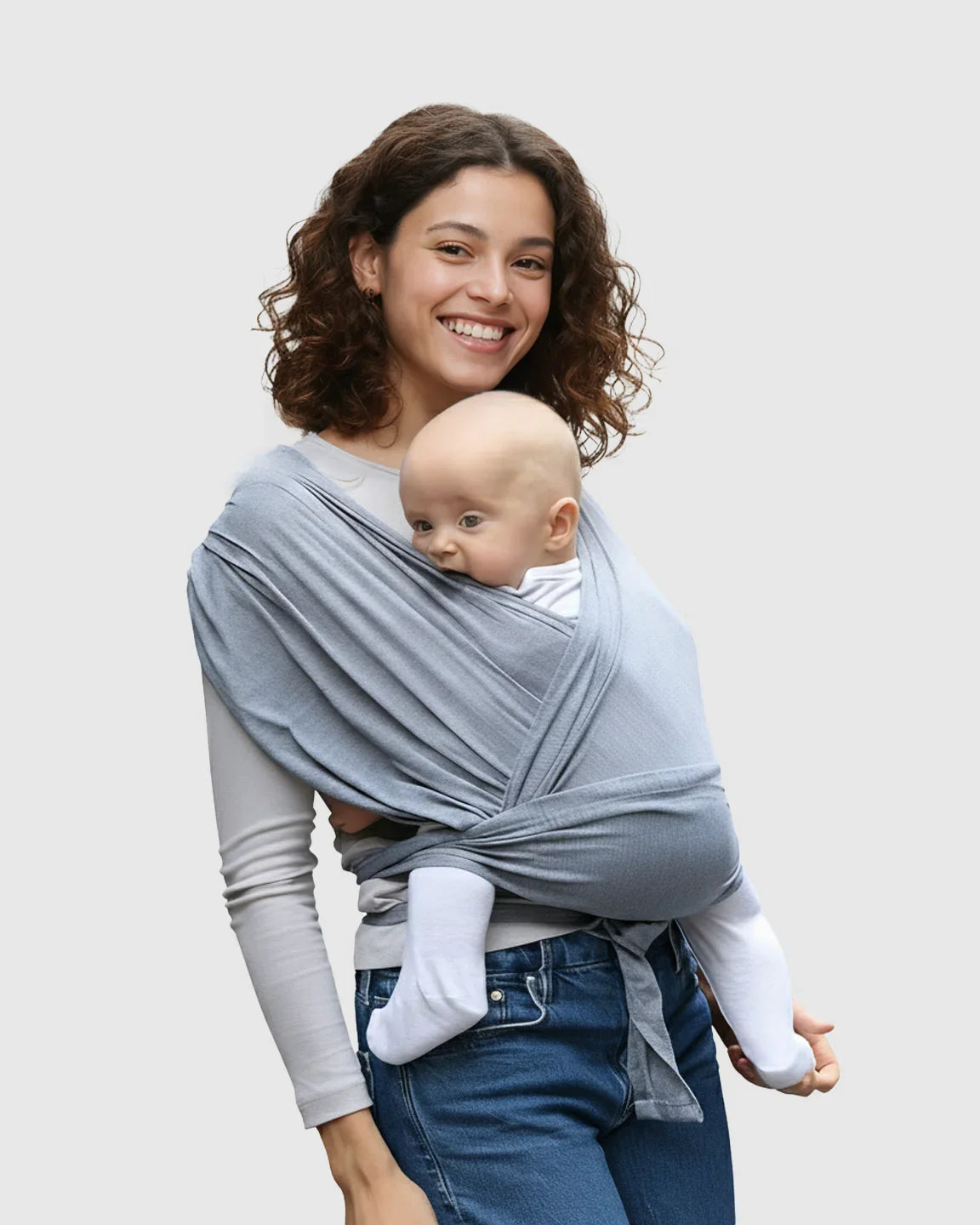 Smiling woman wearing a gray adjustable wrap-around baby carrier with a baby snuggled inside.