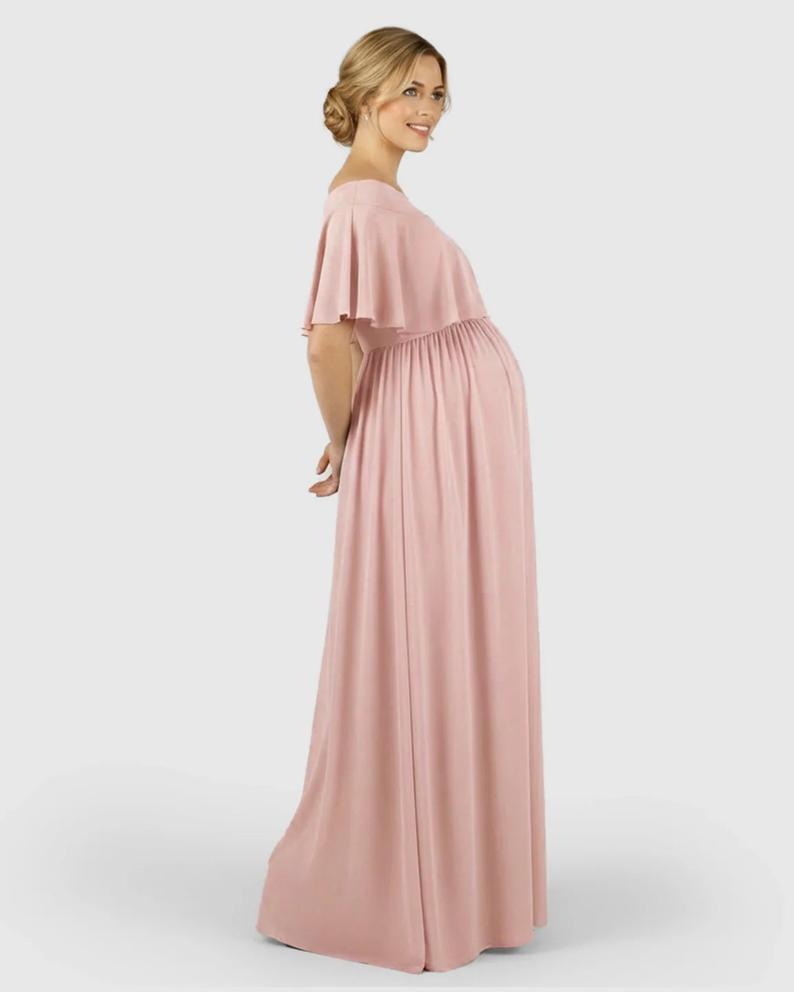 Smiling pregnant woman in a flowy, blush pink off-shoulder chiffon maternity photoshoot dress.
