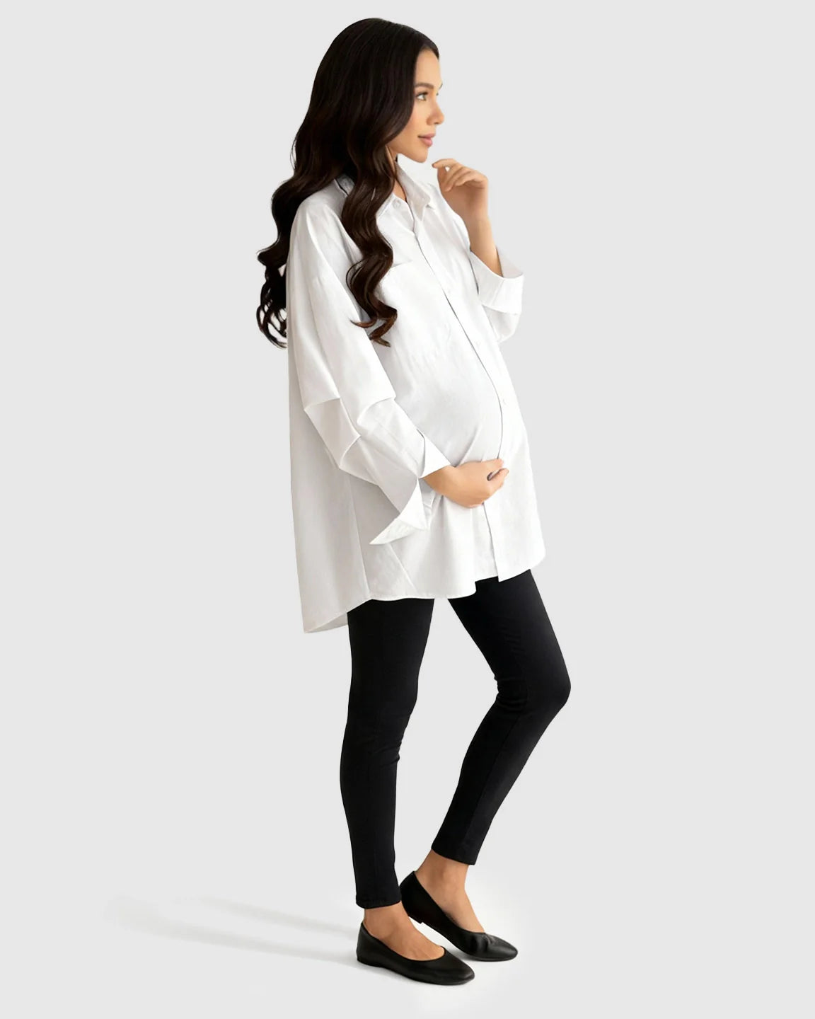 Pregnant woman in white cotton lapel-collar button-front maternity tunic and black leggings.