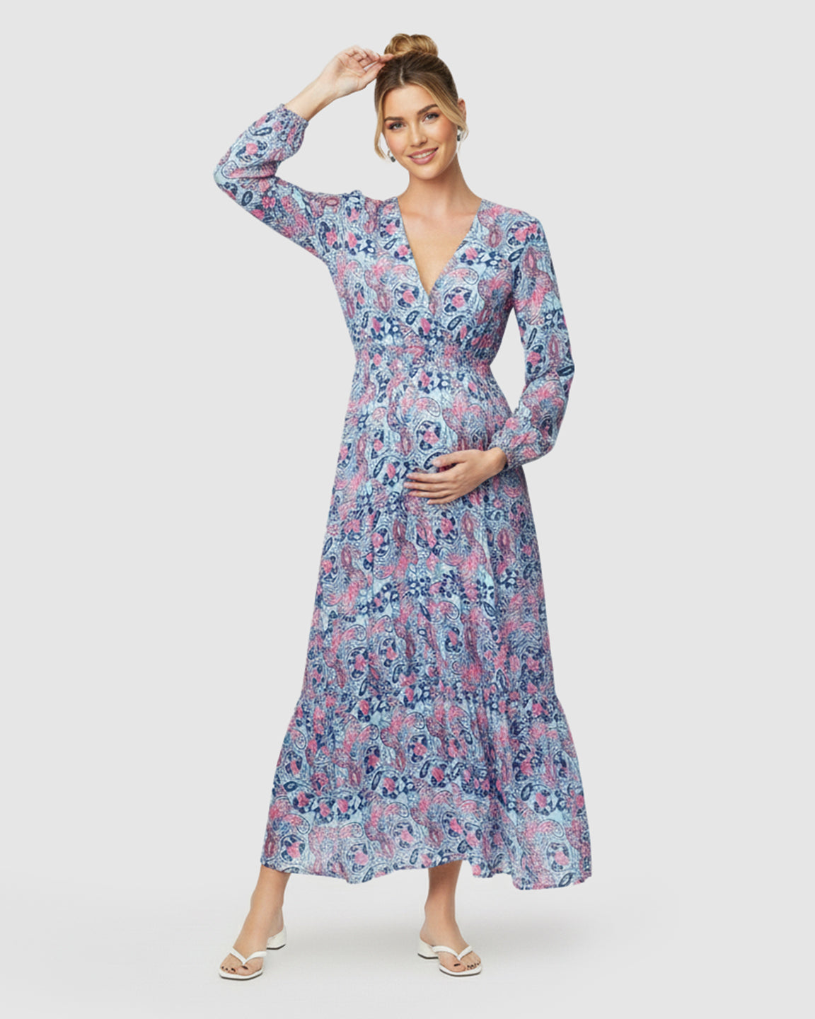 Pregnant woman in a blue and pink paisley flowy maxi dress with a V-neck and tie waist.