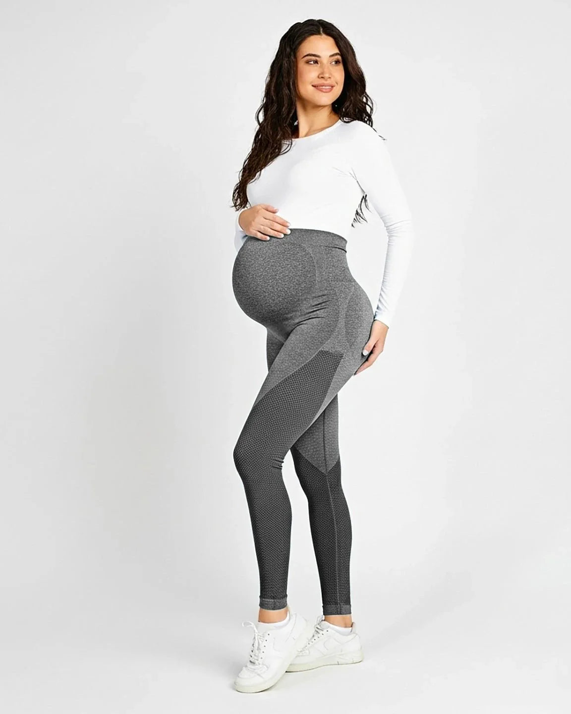 Smiling pregnant woman in gray high-waisted, body-hugging maternity leggings with textured details.