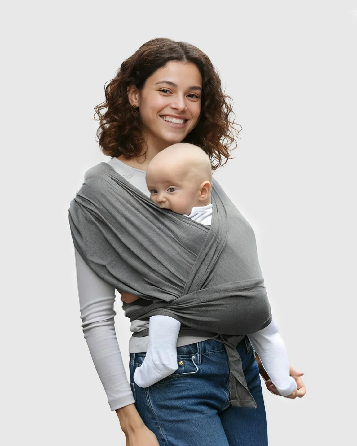 Smiling woman wearing a charcoal gray adjustable wrap-around baby carrier with a baby snuggled inside.