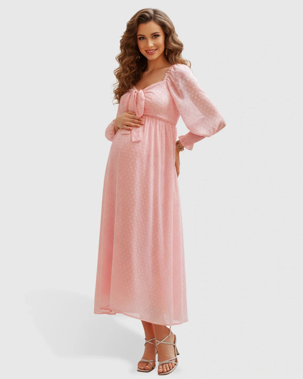 Smiling pregnant woman in a pink polka-dot maternity maxi dress with a square neckline and long sleeves.