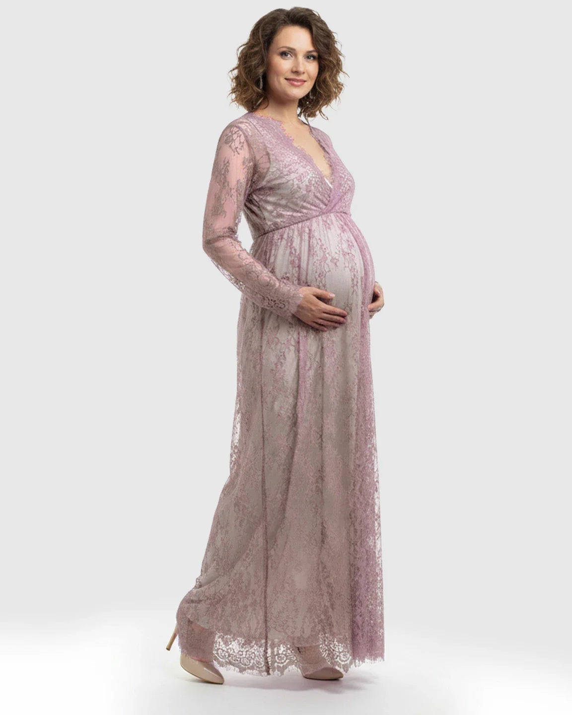 Maternity maxi dress in sheer floral lace, empire waist, V-neck, and long sleeves, worn by a smiling pregnant woman.