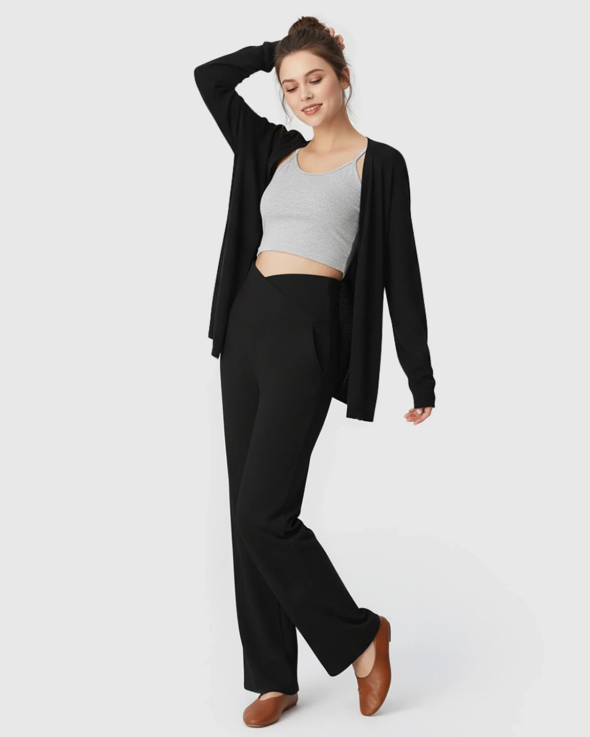 Woman in black crossover waist wide-leg maternity lounge pants, grey crop top, and black cardigan.