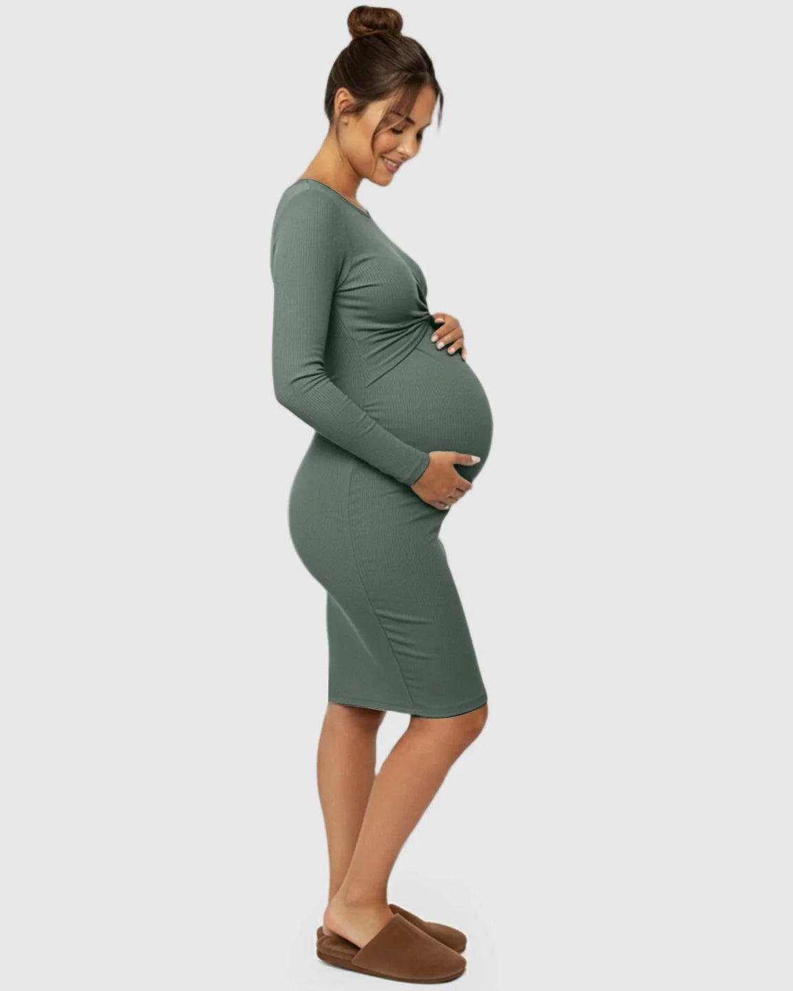 Smiling pregnant woman in a sage green ribbed bodycon maternity dress with a twist-front detail.