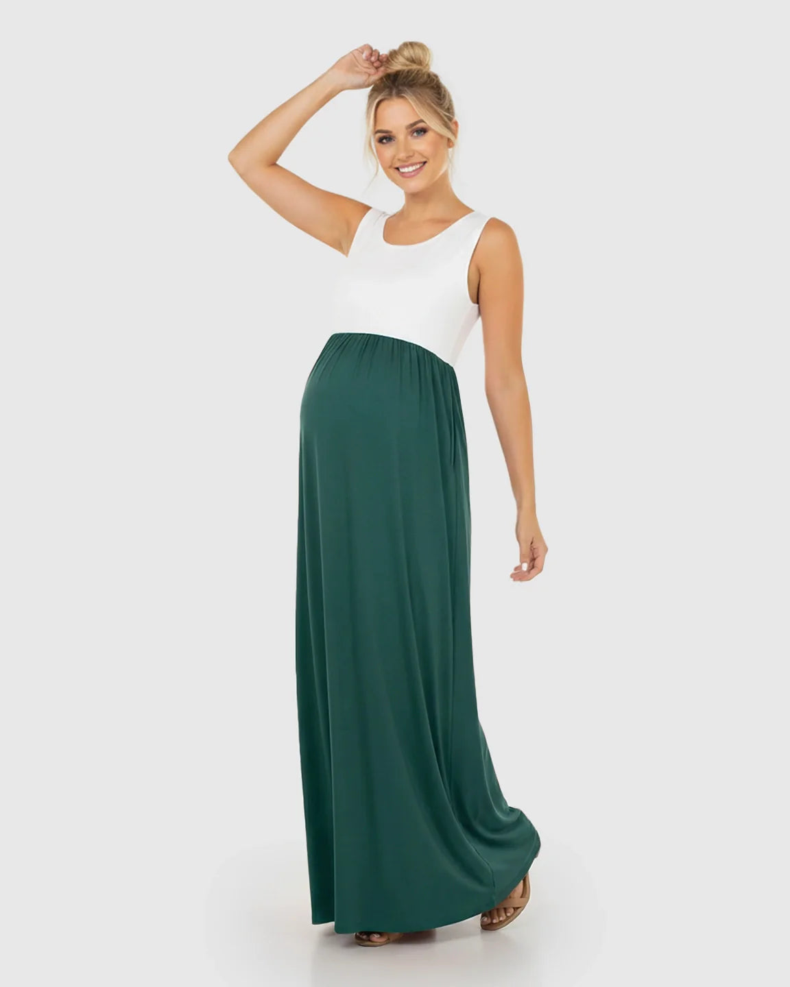 Smiling pregnant woman in a white and dark green colorblock high-waisted maternity maxi dress.