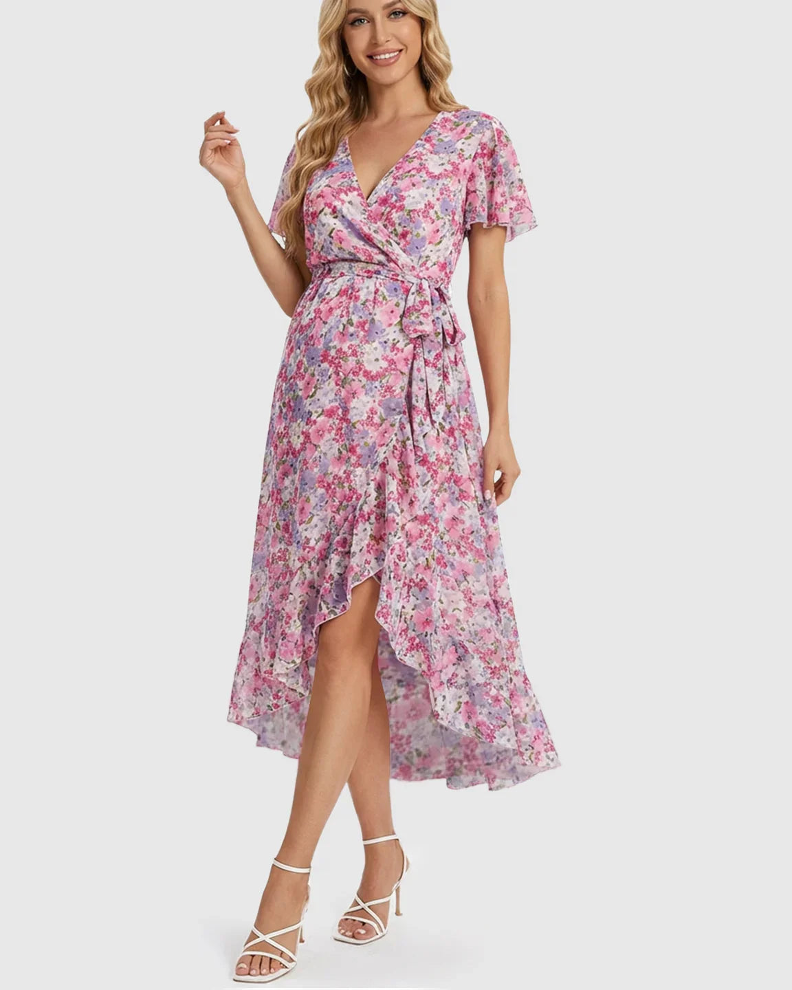 Smiling woman in a pink floral V-neck ruffled hem maternity midi dress with a tie waist.
