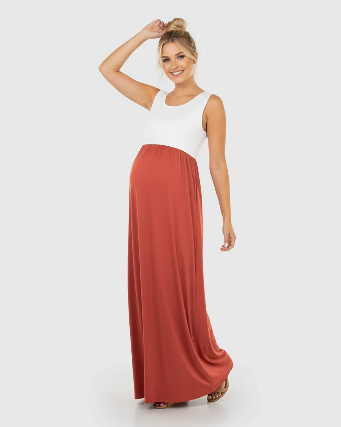 Smiling pregnant woman in a white and rust colorblock high-waisted maternity maxi dress with a flowing skirt.