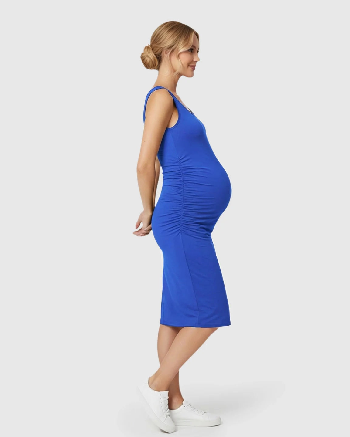 Smiling pregnant woman in a royal blue sleeveless bodycon maternity dress with side ruching.