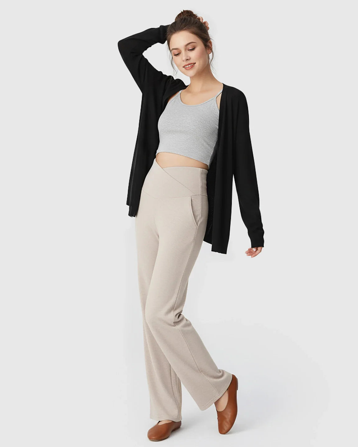 Woman in beige crossover waist wide-leg maternity lounge pants, grey crop top, and black cardigan.