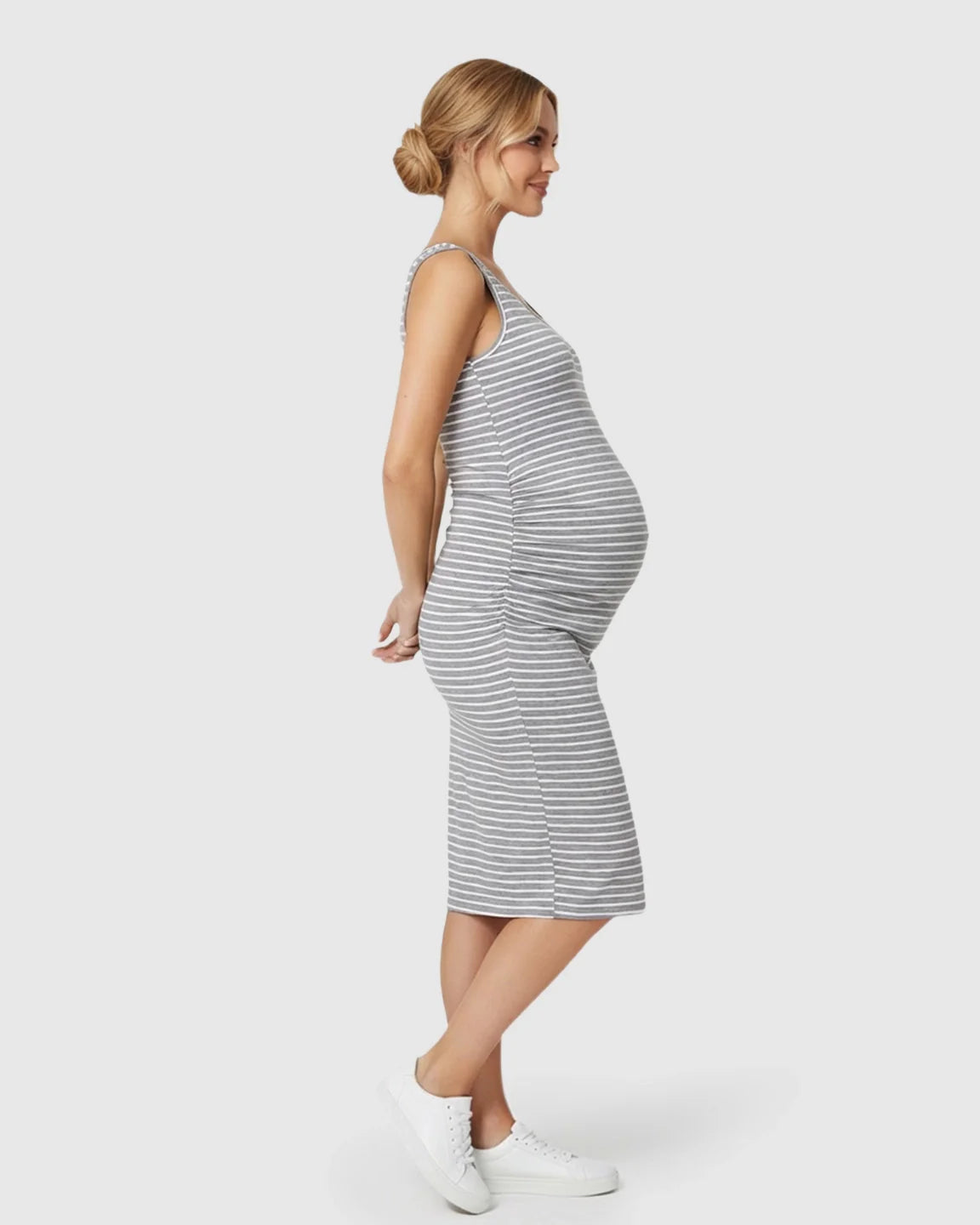 Pregnant woman in a gray and white striped sleeveless bodycon maternity dress with side pleats.