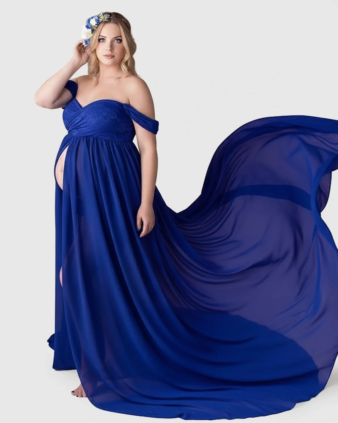 Maternity model in a flowing royal blue off-shoulder chiffon gown with an extra-long train and floral headpiece.